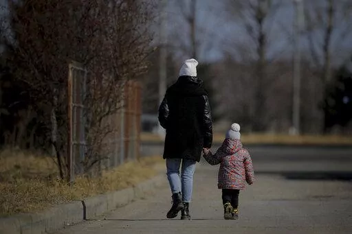 A woman holds a child's hand after crossing the border from Ukraine at the Romanian-Ukrainian border, in Siret, Romania, Friday, Feb. 25, 2022. Thousands of Ukrainians are fleeing from war by crossing their borders to the west in search of safety. They left their country as Russia pounded their capital and other cities with airstrikes for a second day on Friday. Cars were backed up for several kilometers (miles) at some border crossings as authorities in Poland, Slovakia, Hungary, Romania and Mo