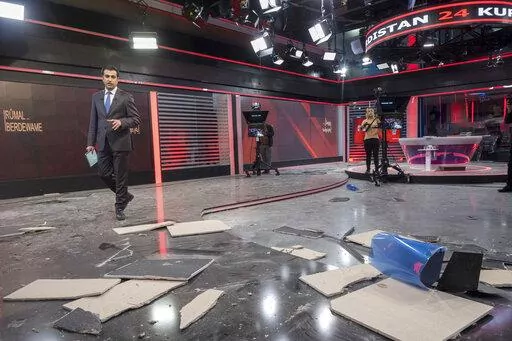 Employees of Kurdistan 24, a satellite television station, work in a studio damaged by an Iranian ballistic missile attack in Irbil, Iraq, Sunday, March 23, 2022. (AP Photo/ Ahmed Mzoori, Metrography)