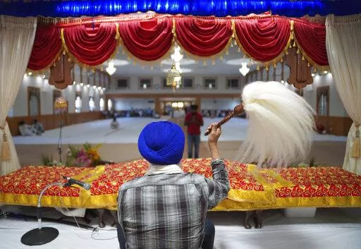 A man waves the Chaur Sahib, paying respect to the sacred scripture, during evening prayer at Gurdwara Millwoods, a Sikh house of worship, in Edmonton, Alberta, on Wednesday, July 20, 2022. (AP Photo/Jessie Wardarski)