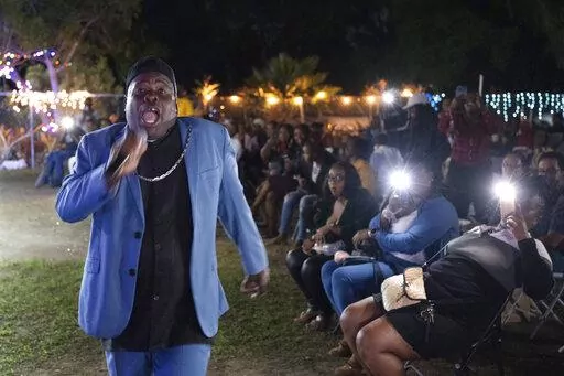 Bishop Lawrence Rolle performs in front of children and adults at Mt. Carmel Preparatory Academy in Nassau, Bahamas on Thursday, Dec. 8, 2022. Rolle's ministry received $50,000 from FTX in early 2022, one of several donations the cryptocurrency exchange made to the Bahamian people when it relocated to the Caribbean island nation in 2021. (AP Photo/Ken Sweet)