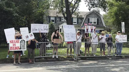 Protesters stand along a street on Long Island in Southampton, N.Y. on Friday, Aug. 17, 2018, near the location of a campaign fundraiser attended by President Donald Trump. (AP Photo/Sara Gillesby, File)