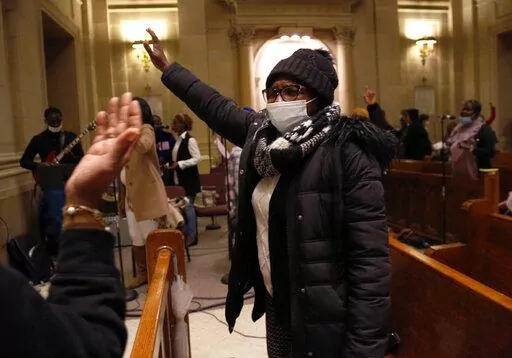 Aline Compaore sings along with the French choir, Chorale Sainte Marie Reine, at the end of Mass at the Church of Notre Dame in New York, on Sunday, March 6, 2022. Today, it is largely African Catholics who worship at the church's French service. (AP Photo/Jessie Wardarski)