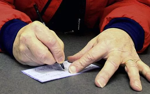 A man signs a check in Anchorage, Alaska, April 17, 2006,. Check fraud tied to mail theft is up nationwide, according to a recent alert. The U.S. Postal Service is vulnerable, and thieves who can access your checks can change the amount and ferret those funds right out of your bank account. (AP Photo/Al Grillo, File)