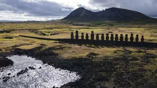 Moai statues stand on Ahu Tongariki near the Rano Raraku volcano, top, on Rapa Nui, or Easter Island, Chile, Nov. 27, 2022. According to Salvador Atan Hito, vice president of the Ma'u Henua Indigenous community which administers the archaeological treasure of Rapa Nui, on March 1, 2023, a small moai was discovered recently in the middle of a dry lagoon inside the volcano's crater. (AP Photo/Esteban Felix, File)