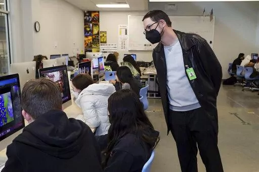In this photo provided by the Hays Consolidated Independent School District, Brian McKinney, right, who has children in the Hays Consolidated Independent School District, in Kyle, Texas, teaches a class at Johnson High School, in Buda, Texas, Thursday, Jan. 27, 2022. McKinney, a small business owner and former teacher, is among parents the district has hired to work as substitute teachers during a staffing crunch. He returned to the classroom after about 15 years away. (Moses Leos III/Hays Conso
