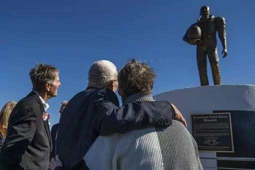 Apollo 13 astronaut Fred Haise Jr., center, hugs sculptor Mary Ott Tremmel Davidson as her statue honoring Haise is unveiled at Biloxi Beach in Biloxi, Miss., Sunday, Feb. 13, 2022. The original ceremony, planned for the 50th anniversary of Apollo 13 in April 2020, was canceled because of COVID-19. Sunday’s event went on despite the death of Haise’s wife, Patt, less than a week before. (Hannah Ruhoff/The Sun Herald via AP)
