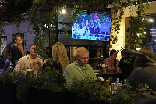 People watch the television broadcast of the opening ceremony of the 2024 Summer Olympics in Paris, France via Kazakhstan satellite channel sitting in the Waterloo pub & bar in St. Petersburg, Russia, Friday, July 26, 2024. Watching the Paris Olympics will be difficult for most people in Russia, and in the view of local media it's not really worth the effort. Russia's state TV channels won't be broadcasting any of the events. (AP Photo/Dmitri Lovetsky)