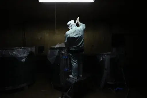 Sake brewer Mie Takahashi stirs mixture of steamed rice with koji mold and water in a tank at her Koten sake brewery in Okaya, central Japan, Saturday, Nov. 30, 2024. (AP Photo/Hiro Komae)