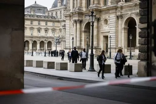 Staff leave the Louvre Museum as people are evacuated after it received a written threat, in Paris, Saturday Oct. 14, 2023. The Louvre Museum says it is closing for the day and evacuating all visitors and staff after a threat. (AP Photo/Thomas Padilla)