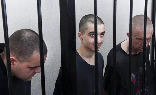 Two British citizens Aiden Aslin, left, and Shaun Pinner, right, and Moroccan Saaudun Brahim, center, sit behind bars in a courtroom in Donetsk, in the territory which is under the Government of the Donetsk People's Republic control, eastern Ukraine, Thursday, June 9, 2022. The two British citizens and a Moroccan have been sentenced to death by pro-Moscow rebels in eastern Ukraine for fighting on Ukraine's side. The three men fought alongside Ukrainian troops and surrendered to Russian forces we