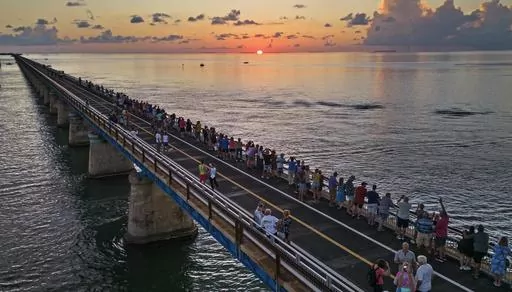 In this aerial photo provided by the Florida Keys News Bureau, attendees watch and toast the sunset at a Florida Keys bicentennial celebration, Friday, May 19, 2023, on the restored Old Seven Mile Bridge in Marathon, Fla. The sunset gathering was among a series of Keys events being staged to mark the 200th anniversary, on July 3, of the Florida Territorial Legislature's 1823 founding of Monroe County, containing the entire island chain. The old bridge was originally part of Henry Flagler's Flori