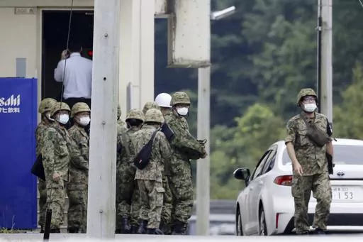 Japanese Self Defense Force members gather near a facility in a base firing range, following a deadly shooting in Gifu, central Japan, Wednesday, June 14, 2023. A Japanese soldier was arrested Wednesday after allegedly shooting three colleagues at an army base in central Japan, officials said. (Kyodo News via AP)