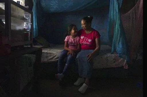 Mariana López sits with her seven-year-old daughter at their home in Ahuachapan, El Salvador, on Thursday, May 19, 2022. In 2000, López says she had an obstetric emergency, but was arrested on suspicion of inducing an abortion. She served 17 years in prison before being released when her 25-year sentence was commuted. (AP Photo/Jessie Wardarski)