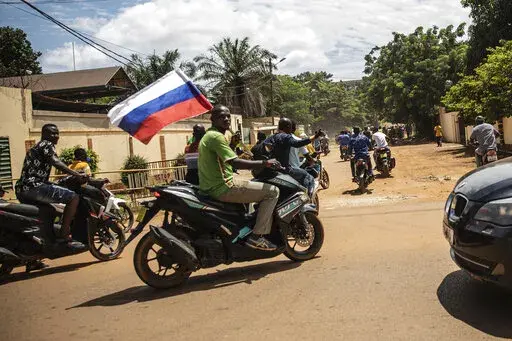 Supporters of Capt. Ibrahim Traore parade waving a Russian flag in the streets of Ouagadougou, Burkina Faso, Sunday, Oct. 2, 2022. Burkina Faso's new junta leadership is calling for calm after the French Embassy and other buildings were attacked. The unrest following the West African nation's second coup this year came after a junta statement alleged that the ousted interim president was at a French military base in Ouagadougou. France vehemently denied the claim and has urged its citizens to st