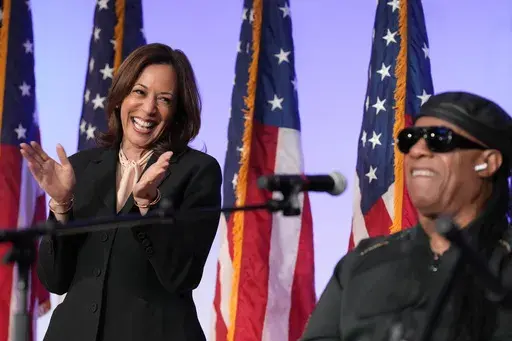 Democratic presidential nominee Vice President Kamala Harris listens as Stevie Wonder performs "Redemption Song" during a church service and early vote event at Divine Faith Ministries International, Sunday, Oct. 20, 2024, in Jonesboro, Ga. (AP Photo/Jacquelyn Martin)