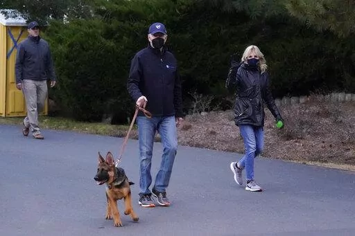 President Joe Biden and first lady Jill Biden take their dog Commander for a walk in Rehoboth Beach, Del., Tuesday, Dec. 28, 2021. (AP Photo/Patrick Semansky)