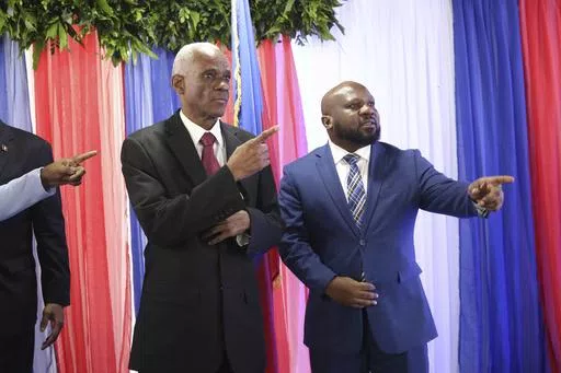 Edgard Leblanc Fils, left, and Smith Augustin prepare to pose for a group photo with the transitional council after it named Fils as its president in Port-au-Prince, Haiti, Tuesday, April 30, 2024. The transitional council will act as the country’s presidency until it can arrange presidential elections sometime before it disbands, which must be by February 2026. (AP Photo/Odelyn Joseph)