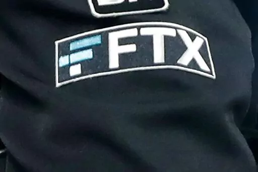 The FTX logo appears on home plate umpire Jansen Visconti's jacket at a baseball game with the Minnesota Twins on Sept. 27, 2022, in Minneapolis. The FTX bankruptcy filing followed a bruising of crypto companies throughout 2022, due in part to rising interest rates and the broader market downturn that has many investors rethinking their lust for risk. (AP Photo/Bruce Kluckhohn, File)