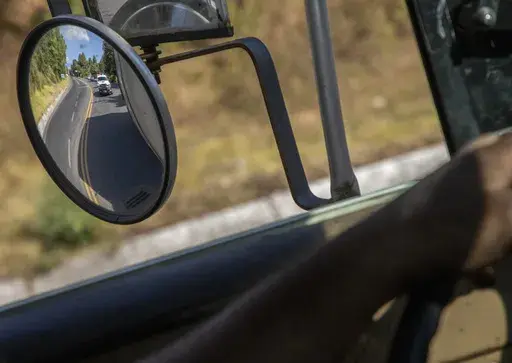 Trucks loaded with avocados are seen reflected on a rear view mirror as they are escorted by the police on their way to the city of Uruapan, in Santa Ana Zirosto, Michoacan state, Mexico, Jan. 26, 2023. (AP Photo/Armando Solis, File)