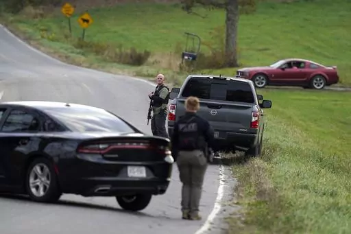 Law enforcement officers hold rifles while investigating a scene, in Bowdoin, Maine, Thursday, Oct. 26, 2023. On Friday, Oct. 27, The Associated Press reported on stories circulating online incorrectly claiming an aerial video of a man lying on his stomach in the middle of a road, being detained by authorities, shows police arresting Maine shooting suspect Robert Card. (AP Photo/Steven Senne, File)