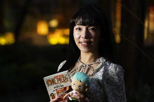 Nina Oiki, a gender and politics researcher at Tokyo's Waseda University, poses for a photo with some of her favorite "One Piece" anime character goods in Tokyo, Sunday, March 5, 2023. Oiki has been a "One Piece" fan since she was in elementary school. Hit Japanese manga “One Piece” is coming to Netflix as a live-action series, a development that's both exciting and worrisome for fans who have seen mixed success in a growing list of Hollywood adaptations. (AP Photo/Hiro Komae)