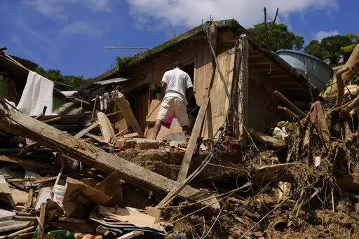 A resident stands on property destroyed by mudslides on the second day of rescue efforts in Petropolis, Brazil, Thursday, Feb. 17, 2022. Deadly floods and mudslides swept away homes and cars, but even as families prepared to bury their dead, it was unclear how many bodies remained trapped in the mud. (AP Photo/Silvia Izquierdo)