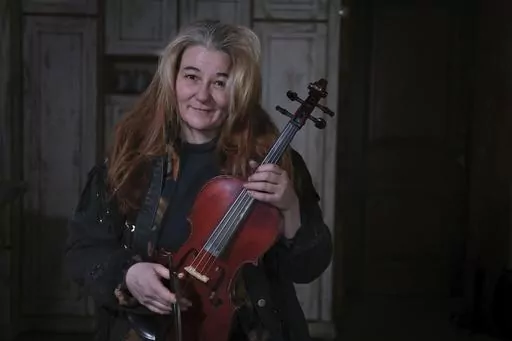 Oksana, 49, who did not want her surname reported, shows a violin she made herself in her small and cold apartment in Bakovka, on the outskirts of Moscow, Russia, Tuesday, Feb. 8, 2022.Oksana's music and colorful instruments lift the spirits of Moscow commuters whose rides are often uncomfortable. (AP Photo/Vitaly Zhiryakov)