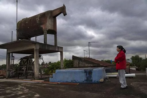 Liliana Gutiérrez looks at the horse-shaped water tank built by her father in the San Jorge neighborhood of Florencio Varela, Argentina, Monday, Oct. 26, 2022. Nostalgia led Gervasio Gutiérrez, a peasant turned bricklayer from the distant province of Jujuy, to build the tank on the terrace of his daughter's house. Before the existence of GPS trackers, the horse-shaped water tank that many confused with a cow, was often used as a reference point for travelers. (AP Photo/Rodrigo Abd)