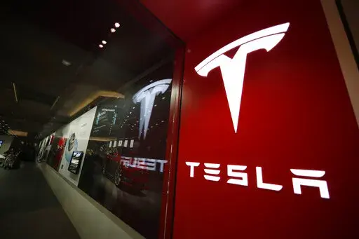 A sign bearing the company logo outside a Tesla store in Cherry Creek Mall in Denver, Feb. 9, 2019. Tesla is looking to split its stock so that the electric vehicle maker can pay a dividend to its shareholders. The company said in a regulatory filing that it plans to make a request at its upcoming annual shareholders meeting to increase its number of authorized shares so that it can split the stock in the form of a dividend. (AP Photo/David Zalubowski, File)