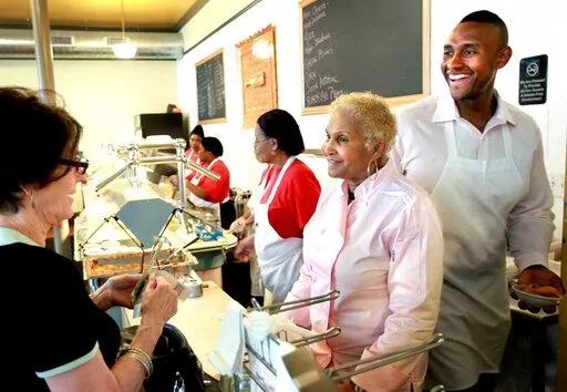 A customer picks up food from Sweetie Pie's owner Robbie Montgomery, second right, and Montgomery's son, James "Tim" Norman, right, at the shop in St. Louis, on April 19, 2011. A St. Louis jury on Friday, Sept. 16, 2022, convicted Norman, a former star of the reality TV show “Welcome to Sweetie Pie’s,” of arranging the shooting death of his nephew. (David Carson/St. Louis Post-Dispatch via AP, File)