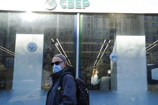 A man walks past an office of Sberbank in Moscow, Russia, Wednesday, March 2, 2022. Ordinary Russians are facing the prospect of higher prices as Western sanctions over the invasion of Ukraine sent the ruble plummeting. (AP Photo/Pavel Golovkin)