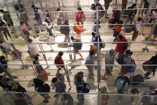 To prevent the spread of COVID-19, plexiglass keeps travelers separated as they make their way through the line to clear security at Love Field in Dallas, Friday, Dec. 31, 2021. (AP Photo/LM Otero)