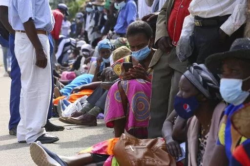 A woman reads messages on her mobile phone while waiting in a bank queue in Harare, Zimbabwe on Monday, Dec. 13, 2021. In Zimbabwe and other African nations, the virus's resurgence is threatening the very survival of millions of people who have already been driven to the edge by a pandemic that has devastated their economies. When putting food on the table is not a given, worries about whether to gather with family members for the holiday or heed public announcements urging COVID-19 precautions 