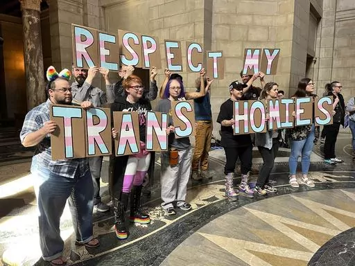 A group of around 200 people who turned out for a rally inside the Nebraska State Capitol hold up signs in support of the transgender community, Friday, March 24, 2023 in Lincoln, Neb. The rally was held to protest the advancement of a bill Thursday that would ban gender-affirming care for minors, as well as a bill that would criminalize allowing minors to attend drag shows. (AP Photo/Margery Beck)