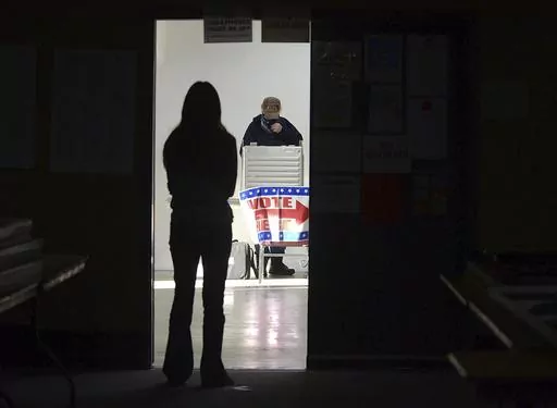A first-time voter waits in the doorway for a voting booth as another voter completes his ballot at the Boot City Opry near Terre Haute, Ind., Nov. 3, 2020. (Joseph C. Garza/The Tribune-Star via AP, File)