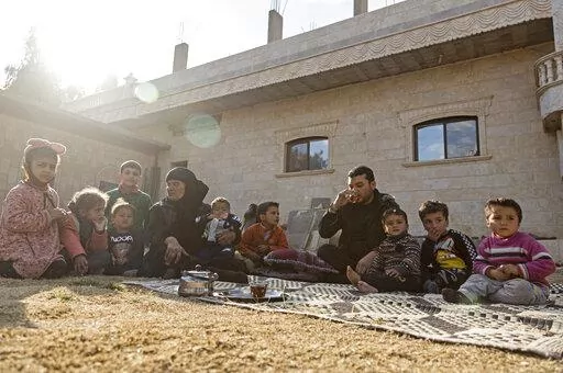 Milhem Daher, 35, drinks tea as he sits with his family outside his house in the village of Kasrat Srour, in the southeastern countryside of the Raqqa province, Syria, Monday, Feb. 7, 2022. Raqqa, the former de facto capital of the self-proclaimed IS caliphate and home to about 300,000, is now free, but many of its residents try to leave. Those with capital are selling their property to save up for the journey to Turkey. Those without money struggle to get by. (AP Photo/Baderkhan Ahmad)