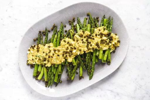 This image released by Milk Street shows a recipe for asparagus covered in Sauce gribiche and fried capers. (Milk Street via AP)