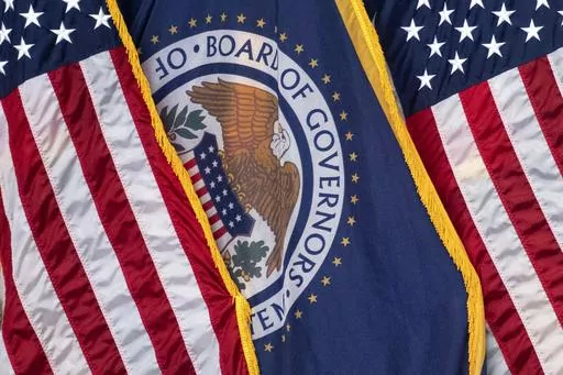 The flag of the Federal Reserve hangs between American flags at a news conference following a Federal Open Market Committee meeting on July 26, 2023 in Washington. On Wednesday, the Federal Reserve releases minutes from the July meeting when it raised its benchmark borrowing rate by another quarter point to 5.4%, the highest level in 22 years. (AP Photo/Nathan Howard, File)