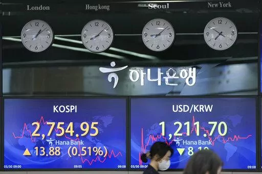 An employee of a bank walks by screens showing the Korea Composite Stock Price Index (KOSPI), left, and the foreign exchange rate between U.S. dollar and South Korean won at a foreign exchange dealing room in Seoul, South Korea, Wednesday, March 30, 2022. Asian stock markets followed Wall Street higher on Wednesday as talks on ending Russia's war on Ukraine appeared to make progress. (AP Photo/Lee Jin-man)