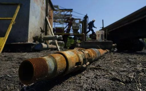 An oil well worker moves equipment at a site on the Rooke family ranch where an orphaned well was plugged, Tuesday, May 18, 2021, near Refugio, Texas. The Interior Department is giving 24 states a total of $560 million to start cleaning high-priority derelict oil and gas wells abandoned on state and private land, the department said Thursday, Aug. 25, 2022. (AP Photo/Eric Gay, File)