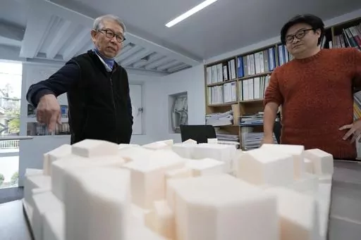 Japan's Riken Yamamoto, left, laureate of Pritzker Architecture Prize, speaks with his staff member near a scale model of a building at his office Wednesday, March 6, 2024, in Yokohama near Tokyo. The Pritzker Architecture Prize has been awarded to Japan’s Riken Yamamoto, who earns the field’s highest honor for what organizers called a long career focused on "multiplying opportunities for people to meet spontaneously, through precise, rational design strategies." (AP Photo/Eugene Hoshiko)
