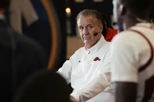 Arkansas head coach John Calipari is interviewed on an ESPN set with his players during the Southeastern Conference NCAA college basketball Media Day in Birmingham, Ala., Tuesday, Oct. 15, 2024. (AP Photo/Gary Cosby Jr., Tuscaloosa News)