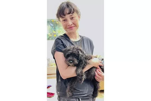 In this undated photo provided by the family of Jade Young and distributed by the New South Wales Police Jade Young holds a dog at an unknown location. Young, 47, was killed in a deadly attack at a Sydney shopping center on Saturday, April 13, 2024. (Courtesy of Young Family/NSW Police via AP)