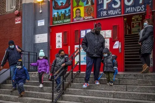 Children and their guardians leave P.S. 64 in the East Village neighborhood of Manhattan, Tuesday, Dec. 21, 2021, in New York. (AP Photo/Brittainy Newman, File)