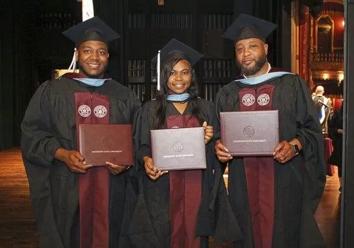 In this photo provided by Mississippi State University - Meridian Office of Public Affairs, Ja'Coby Cole, left, his sister Iesha Gully and their father Commondre Cole, right, show their diploma covers, on Thursday, May 12, 2022, during the school's commencement at the MSU Riley Center in Meridian, Miss. Each of the three earned a master's degree in education. (Lisa Sollie/Mississippi State University - Meridian via AP)