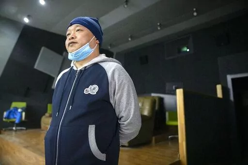 Lan Bo, director of the documentary film "Wuhan, I Am Here," stands in a screening room before a viewing of his movie in Beijing, Saturday, Jan. 15, 2022. The homeless, the sick, the elderly: For people who fell through the cracks of the official system, the then-unprecedented decision to isolate the central Chinese city of Wuhan and its 13 million people was a matter of life or death. Director Lan Bo hopes to sound the alarm with a documentary about volunteers who helped neighbors get food and 