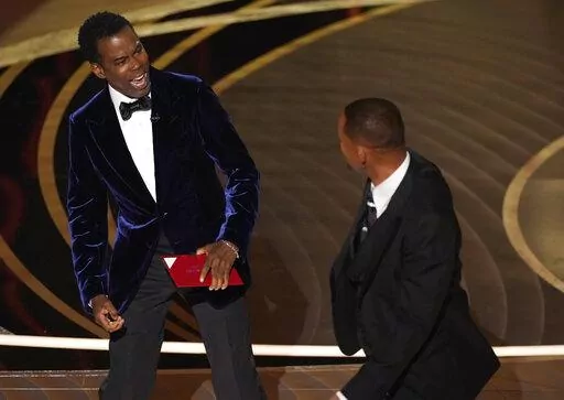 Presenter Chris Rock, left, reacts after being hit on stage by Will Smith while presenting the award for best documentary feature at the Oscars on Sunday, March 27, 2022, at the Dolby Theatre in Los Angeles. (AP Photo/Chris Pizzello)
