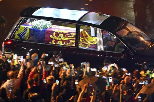 The coffin of Queen Elizabeth II in the royal hearse travels to Buckingham Palace in London, Tuesday Sept. 13, 2022. (Marco Bertorello/Pool via AP)