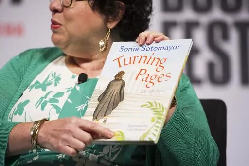 Supreme Court Justice Sonia Sotomayor holds her children's book, "Turning Pages: My Life Story", while speaking to an audience at the Library of Congress National Book Festival in Washington, Sept. 1, 2018. (AP Photo/Cliff Owen, File)