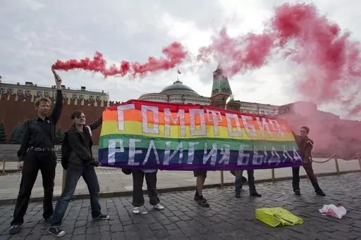 Gay rights activists hold a banner reading "Homophobia - the religion of bullies" during their action in protest at homophobia, on Red Square in Moscow, Russia, on July 14, 2013. Russian lawmakers have approved a toughened version of a bill that outlaws gender transitioning procedures, with added clauses that mandate annulling marriages in which one person has "changed gender" and barring transgender people from becoming foster or adoptive parents. (AP Photo/Evgeny Feldman, File)